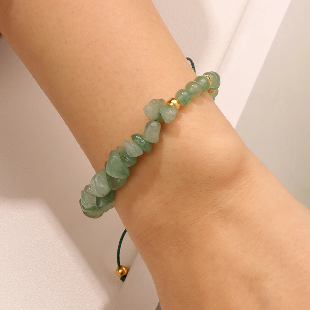 Green beaded bracelet on a wrist against a neutral background