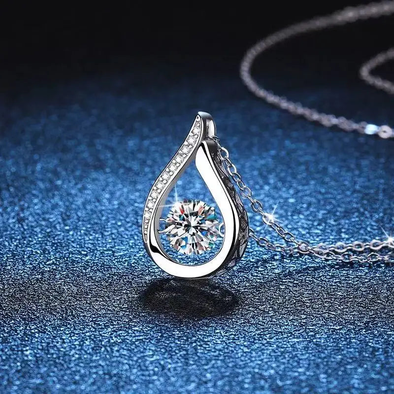 Silver teardrop-shaped pendant with a diamond on a dark blue textured surface