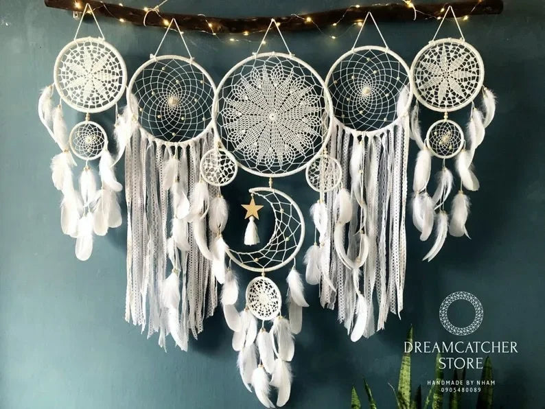 Set of dreamcatchers with feathers against a dark blue wall.