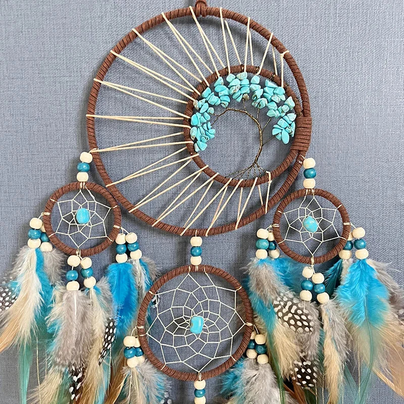 Dreamcatcher with turquoise stones, feathers, and beads on a gray background