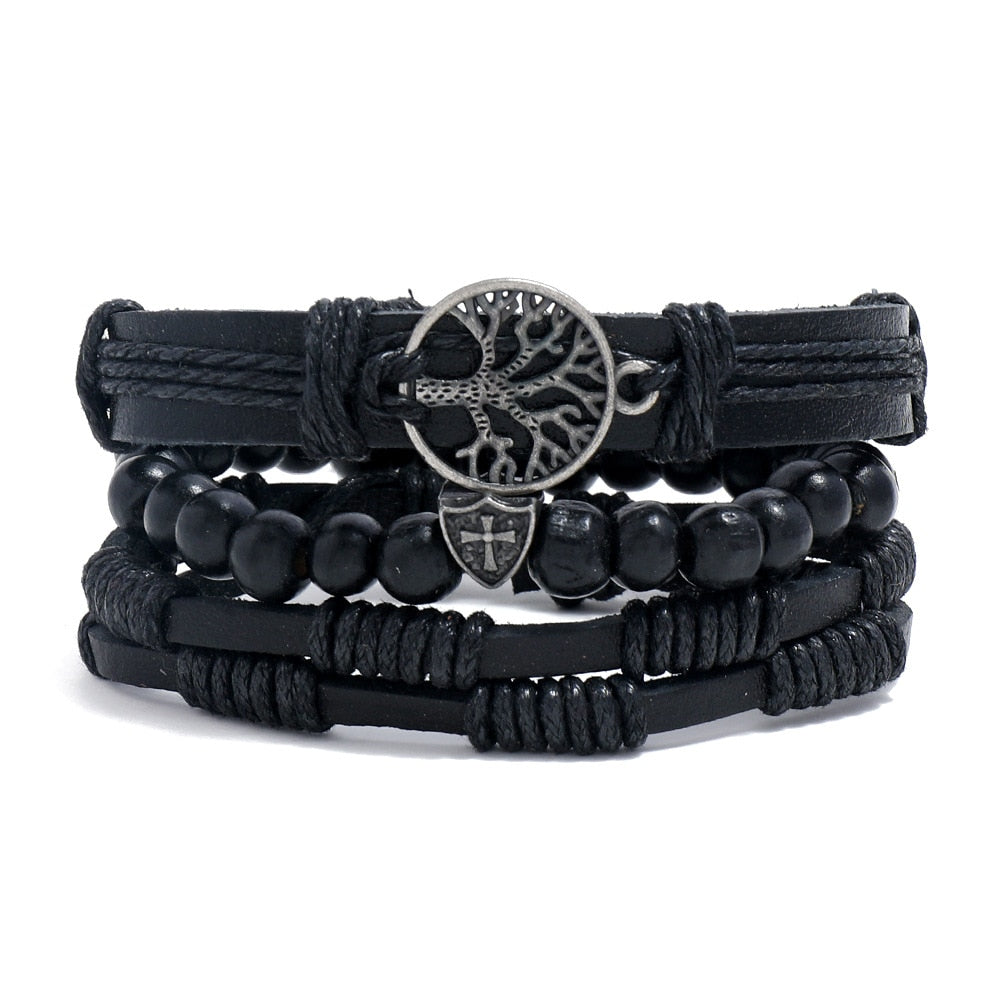 Stack of black bracelets with central metal tree-of-life design on a white background