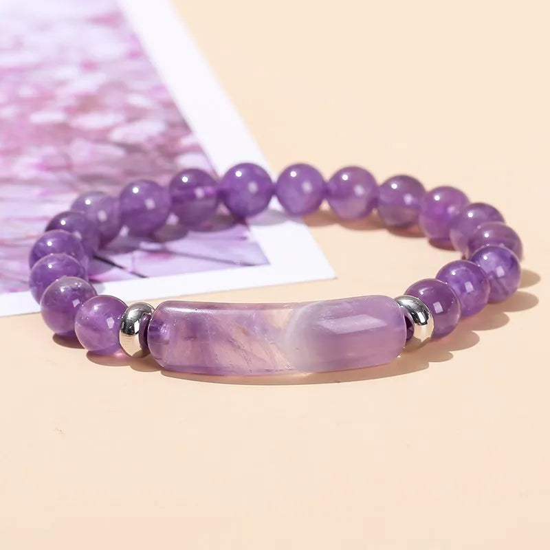 Purple beaded bracelet with silver accents on a light pink background