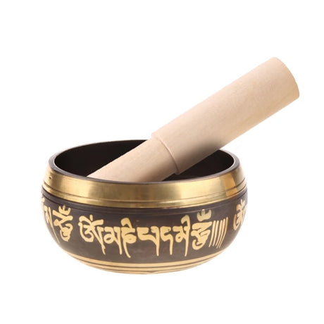 Tibetan singing bowl with gold script and wooden striker on a white background