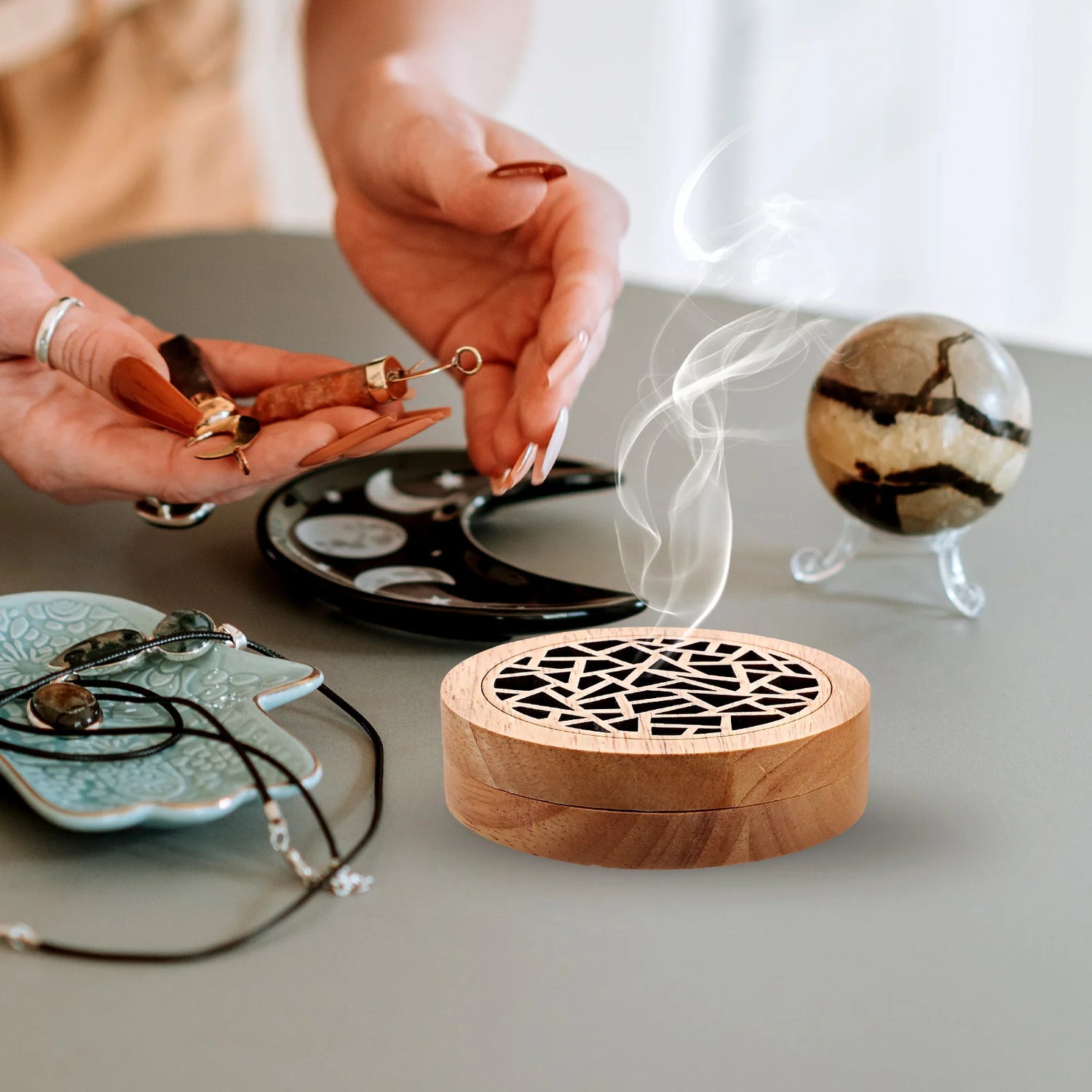 Wooden incense burner with smoke, jewelry, and decorative items on a table.