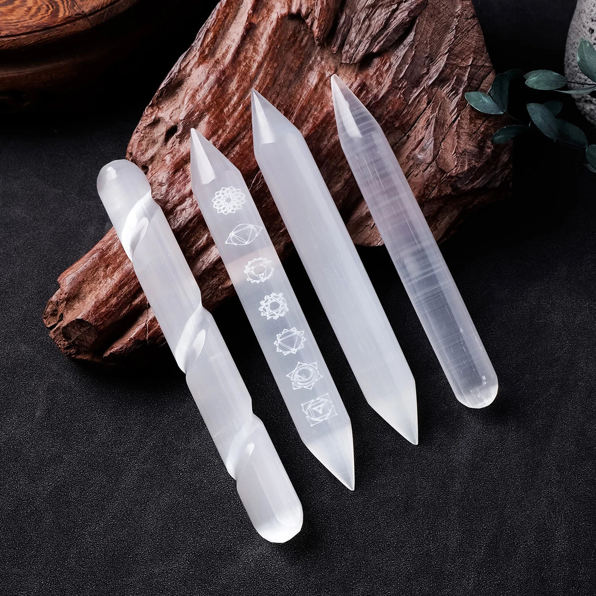 Set of five clear crystal tools with engraved symbols on a dark surface with a wooden log.