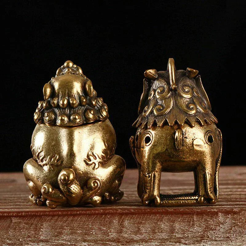Two brass figurines on a wooden surface with a dark background