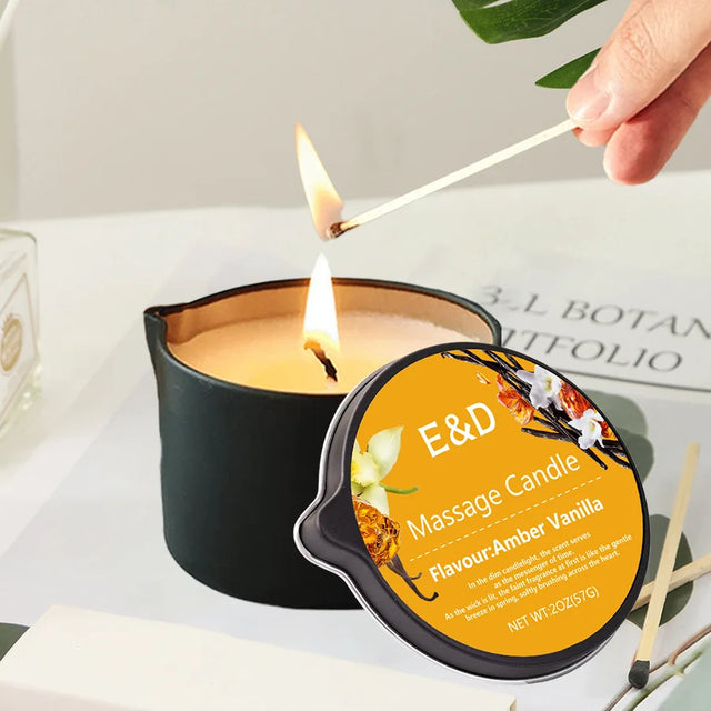 Person lighting a massage candle labeled 'E&D' with a black lid and yellow label.