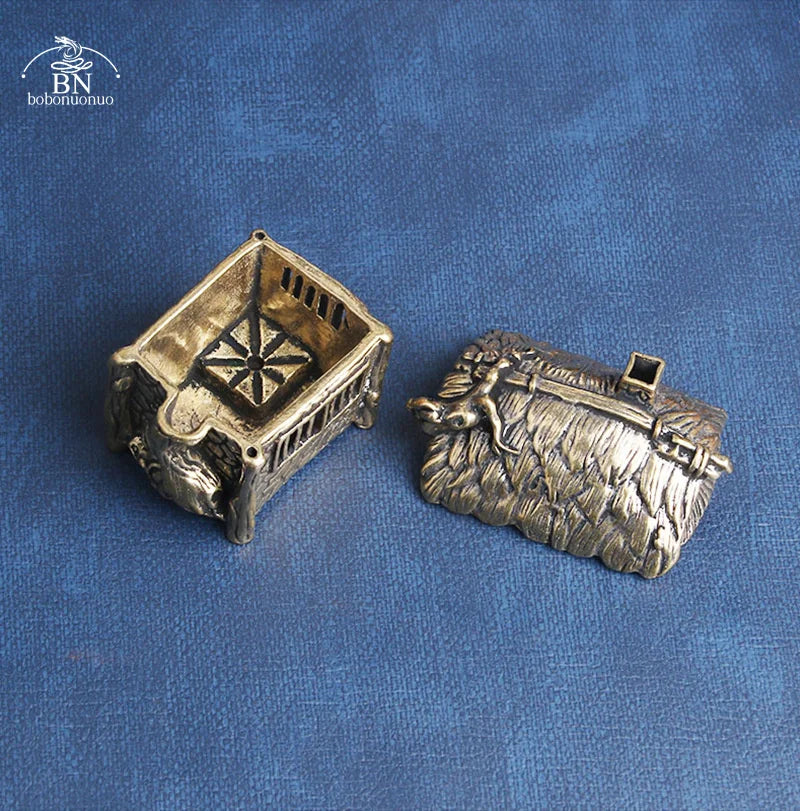 Two bronze figurines of a dog and a crate on a blue fabric background