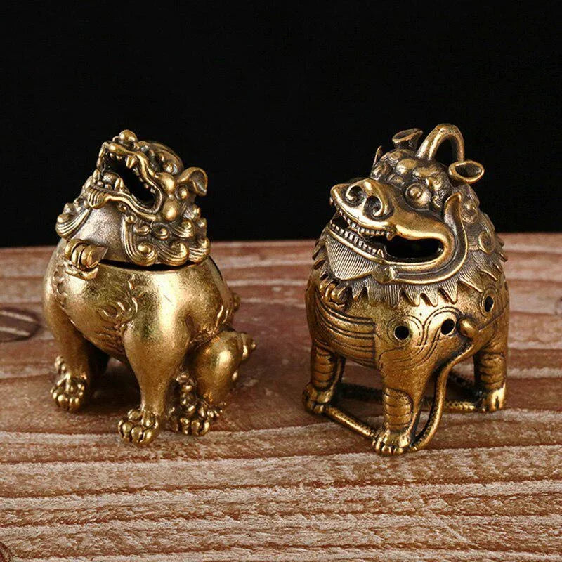 Two brass lion dog statues on a wooden surface with a dark background