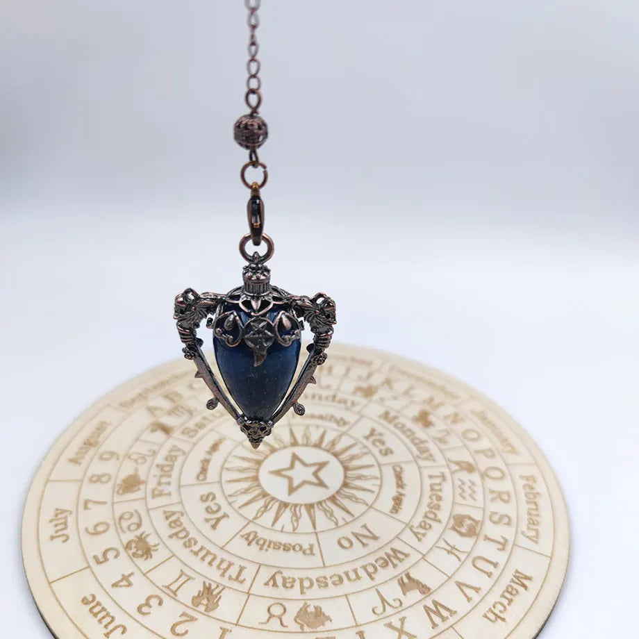 Decorative pendant with blue stone on a circular etched surface with text and symbols