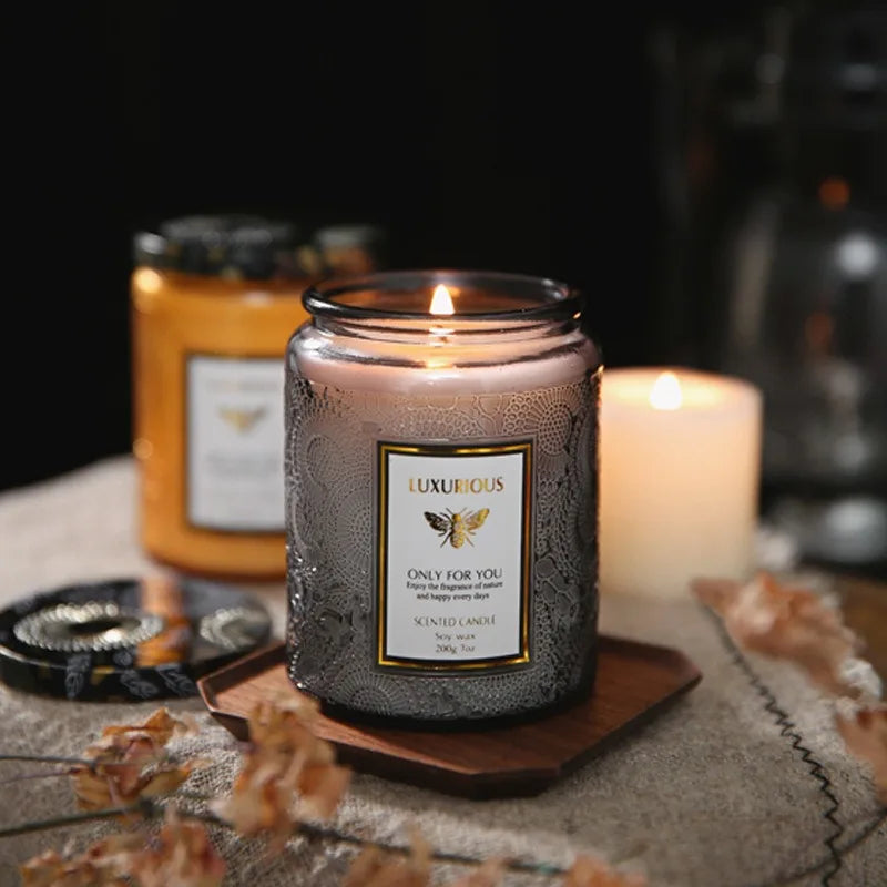 Luxurious scented candle with a label on a wooden coaster, surrounded by other candles and decorative items.