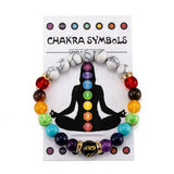Chakra symbol bracelet on a card with colorful beads and black silhouette of a meditating person.