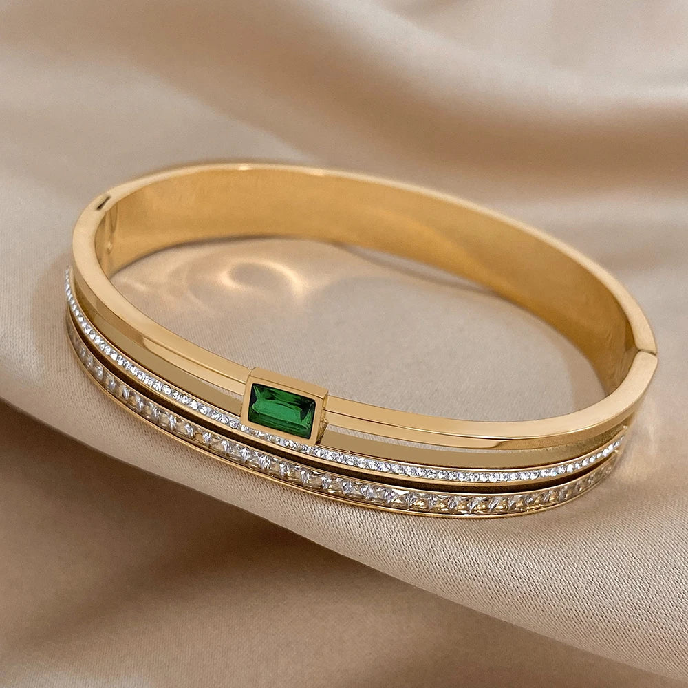 Gold bracelet with emerald and diamonds on a beige fabric background