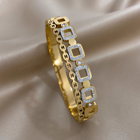 Gold bracelet with square links and small diamonds on a beige fabric background
