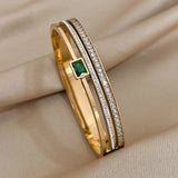 Gold bracelet with emerald and diamonds on a beige fabric background