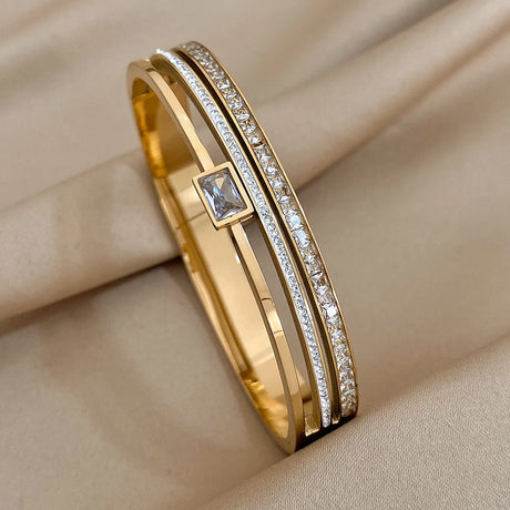 Gold bracelet with diamond accents on a beige fabric background