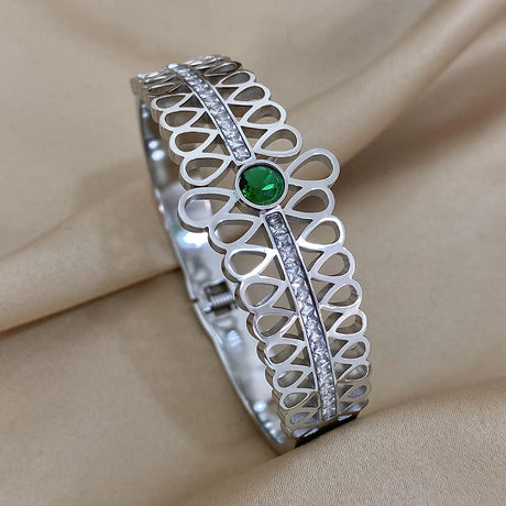 Silver bracelet with a green gemstone on a beige fabric background