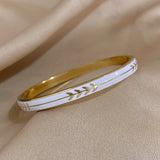 Gold and white bracelet on a beige fabric background