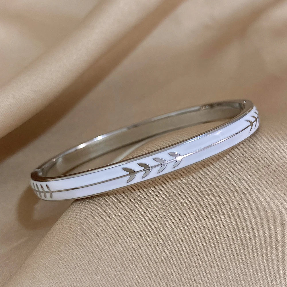 Silver bracelet with leaf pattern on a beige fabric background