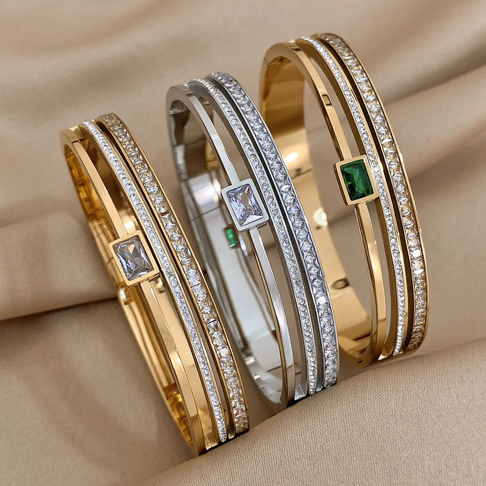 Three gold and silver bracelets with gemstones on a beige fabric background