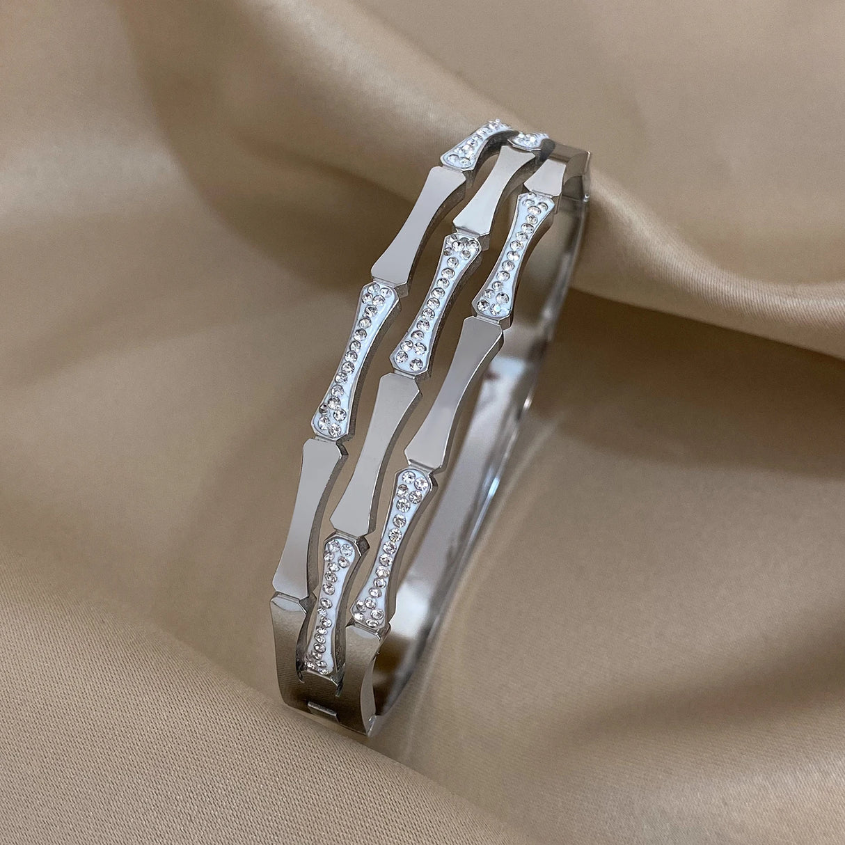 Silver bracelet with diamond accents on a beige fabric background