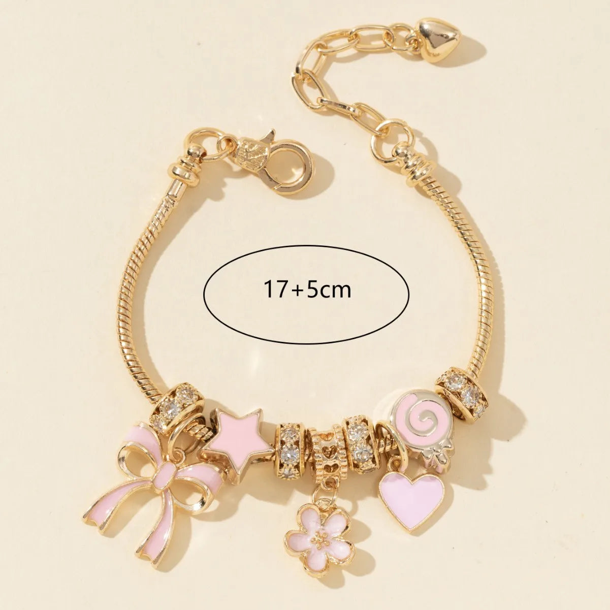 Gold bracelet with pink charms on a beige background