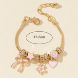 Gold bracelet with pink charms on a beige background