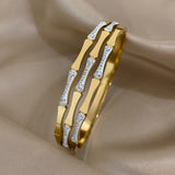 Gold bracelet with diamond accents on a beige fabric background