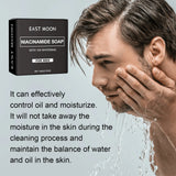Man washing his face with a box of East Moon Niacinamide Soap on a light gray background