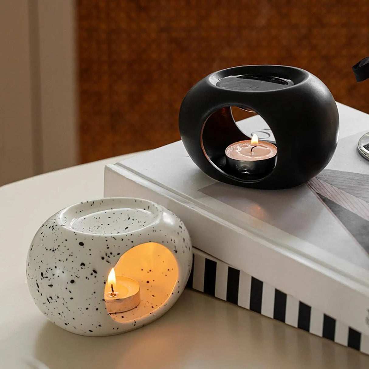 Two ceramic candle holders with lit candles on a surface.