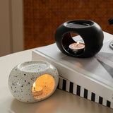 Two ceramic candle holders with lit candles on a surface.