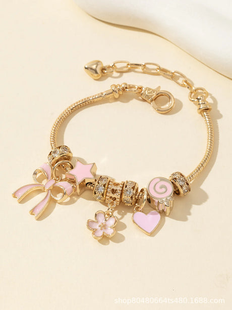 Gold bracelet with pink charms on a light beige background