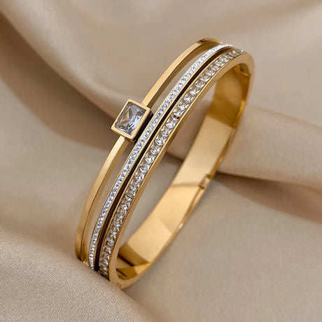 Gold bracelet with diamond accents on a beige fabric background