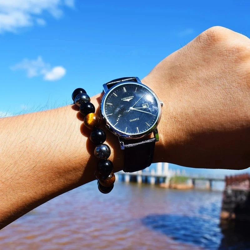 Person wearing a black wristwatch with a scenic background