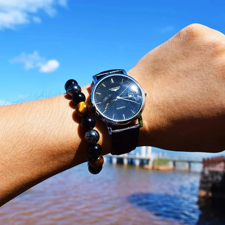 Person wearing a black wristwatch with a scenic background