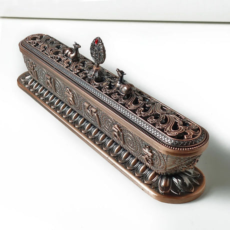 Decorative bronze incense holder with intricate designs on a white background