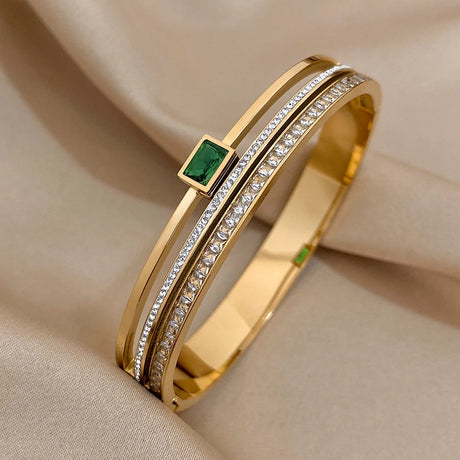 Gold bracelet with a green gemstone on a beige fabric background
