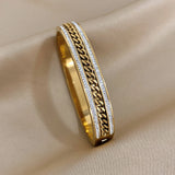 Gold bracelet with chain design on a beige fabric background