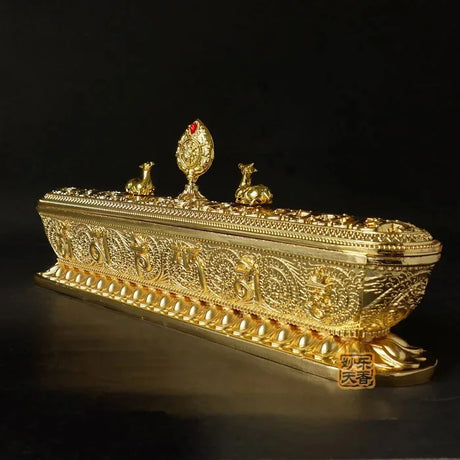 Decorative gold box with intricate designs and small figurines on a black background