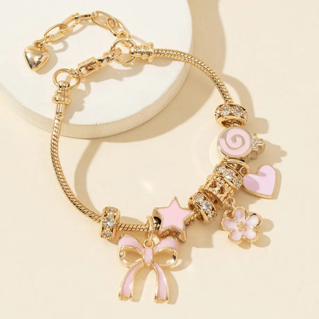Gold bracelet with pink and heart-shaped charms on a beige background
