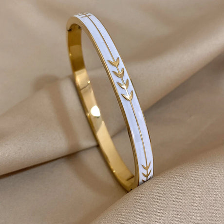 Gold bracelet with white engraving on a beige fabric background