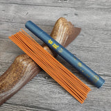 Blue incense stick holder with orange incense sticks on a wooden surface