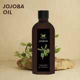 Bottle of jojoba oil with a black label featuring green leaves on a beige background