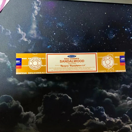 Box of Satya Sandalwood incense on a dark background with smoke effect