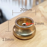 Brass-colored metal component with measurements on a wooden surface