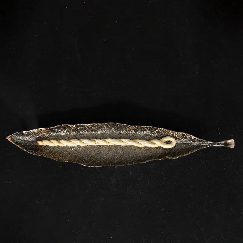 Decorative leaf with braided  incense rope on a black background