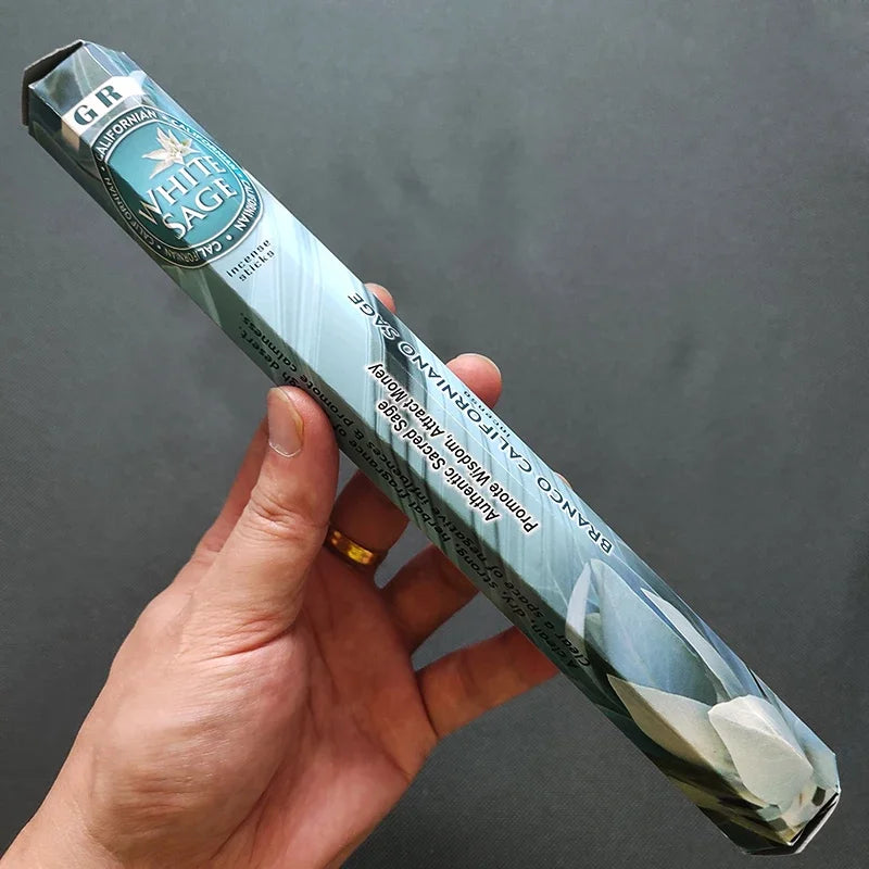 Hand holding a package of G&R White Sage incense against a dark background