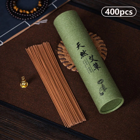 Green cylindrical container with incense sticks on a dark surface