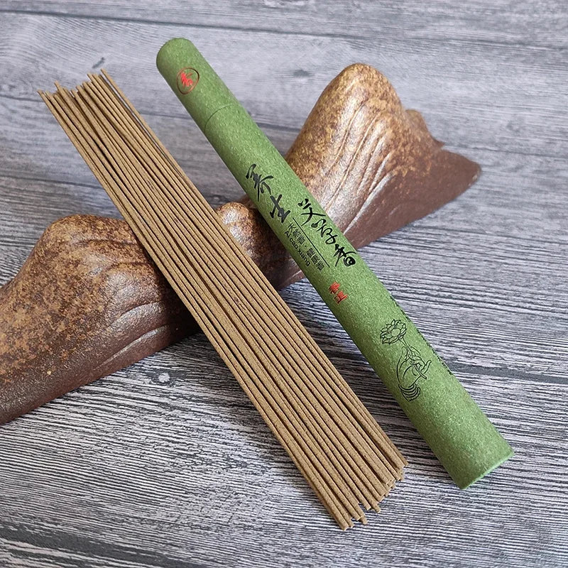 Green incense stick container with incense sticks on a wooden surface