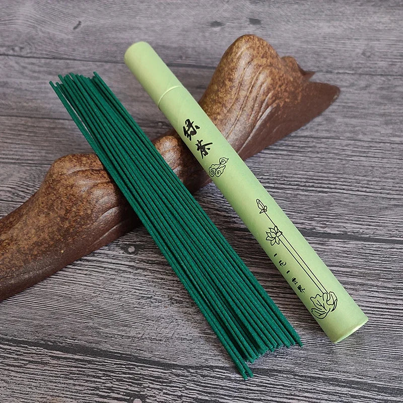 Green incense sticks with a green cylindrical container on a wooden surface
